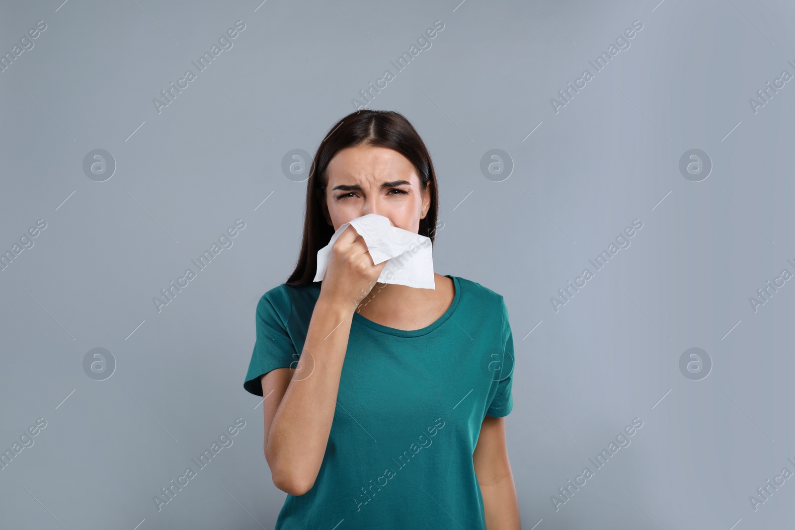 Photo of Young woman suffering from allergy on grey background