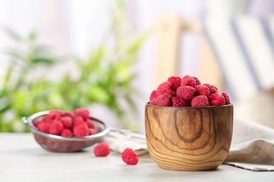 Photo of Bowl with ripe aromatic raspberries on table