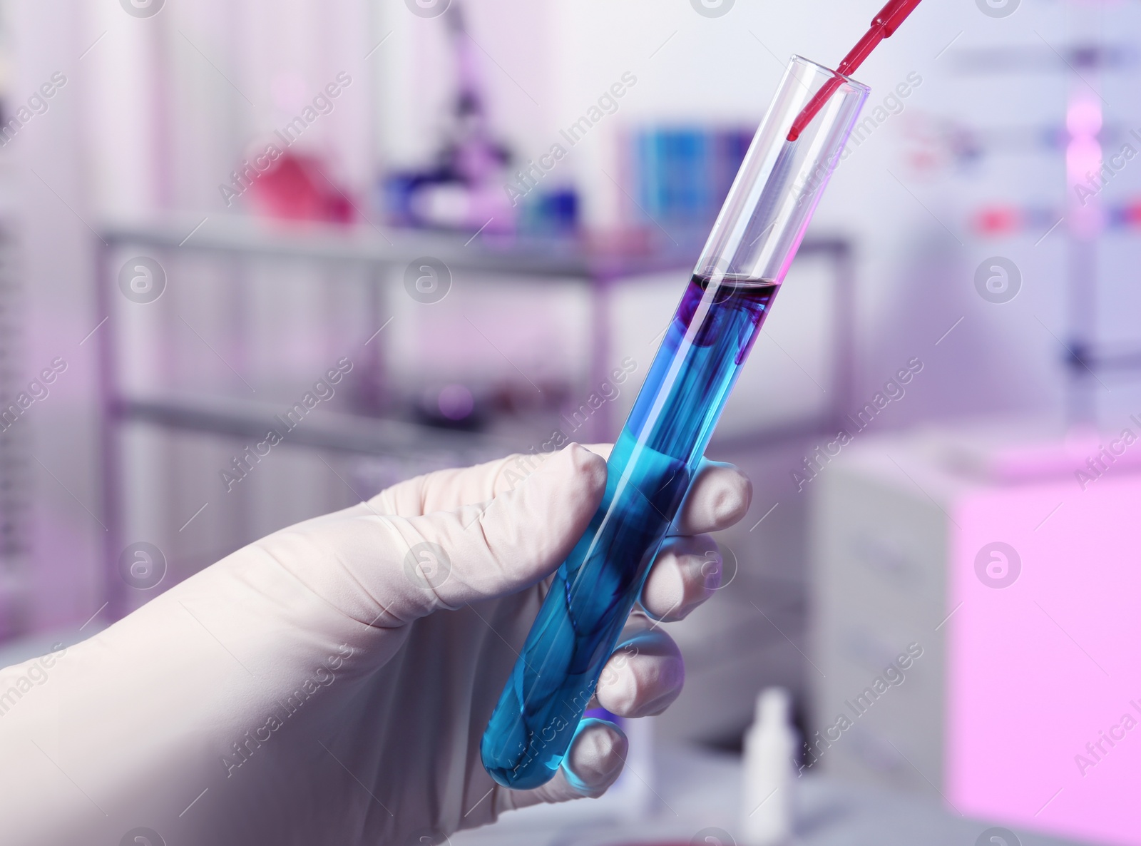 Photo of Scientist dripping reagent into test tube with sample in chemistry laboratory, closeup