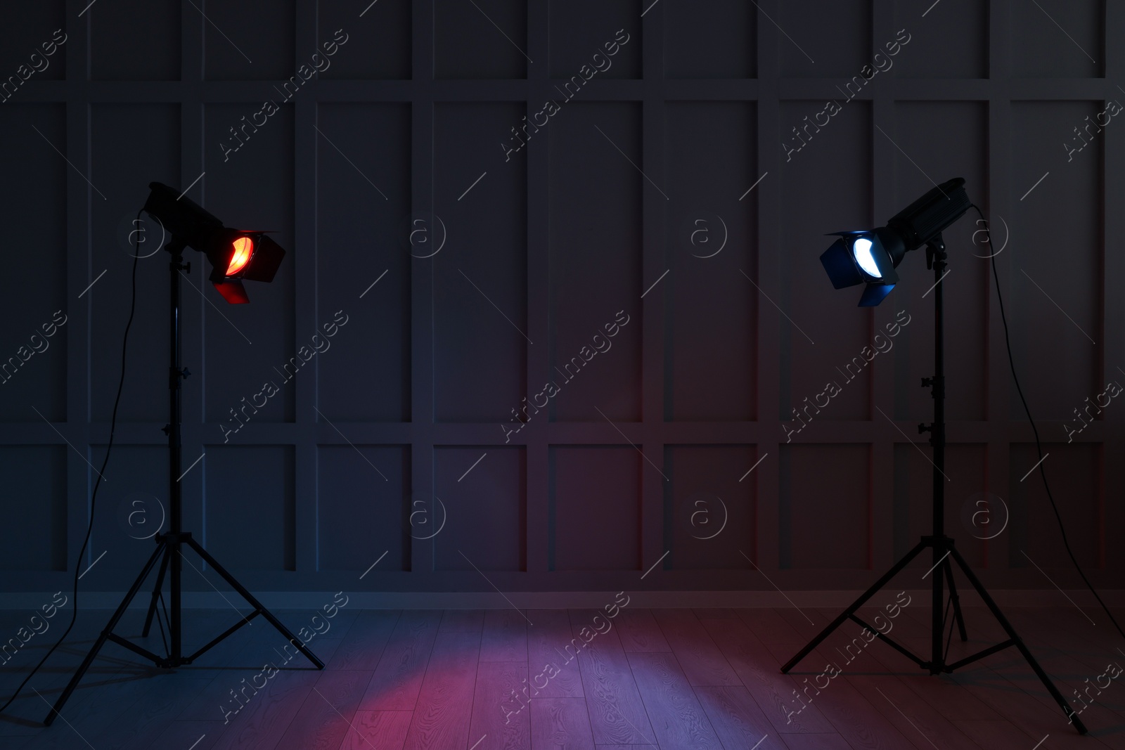 Photo of Bright red and blue spotlights near wall in dark room, space for text