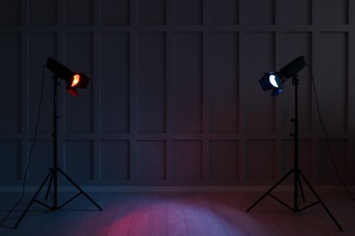 Photo of Bright red and blue spotlights near wall in dark room, space for text