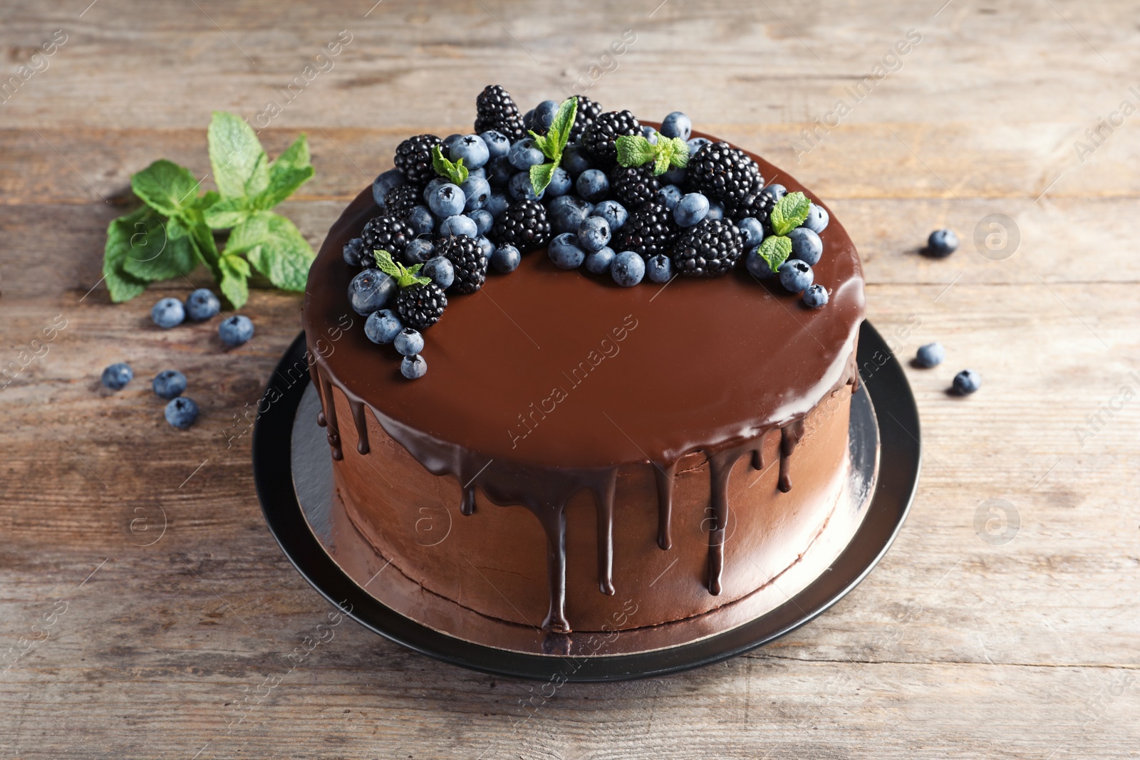 Photo of Fresh delicious homemade chocolate cake with berries on wooden table