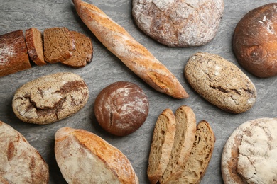 Photo of Different kinds of fresh bread on grey table, flat lay