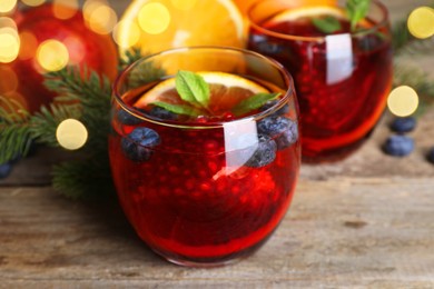 Photo of Aromatic Christmas Sangria drink in glasses on wooden table, closeup