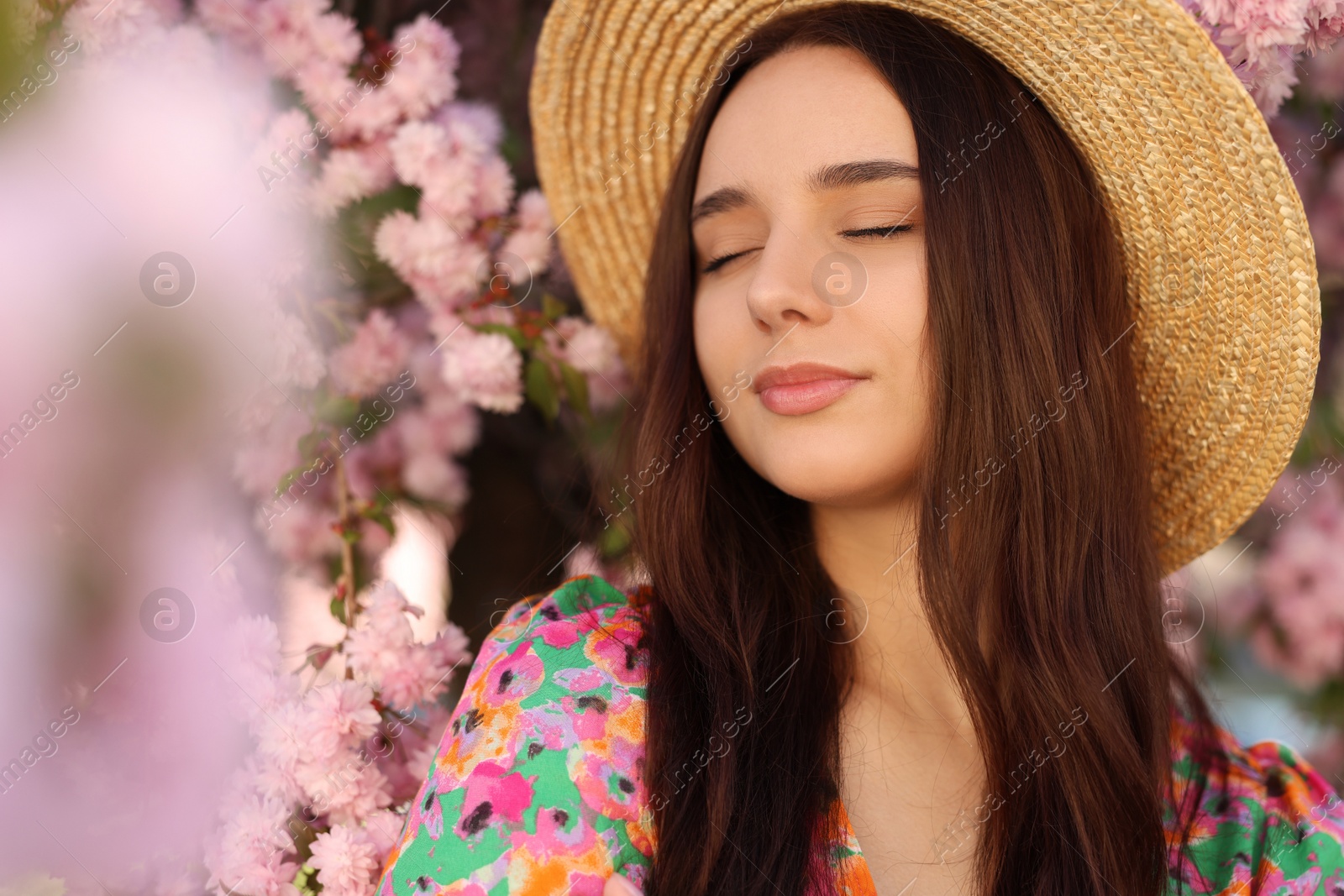 Photo of Beautiful woman in straw hat near blossoming tree on spring day