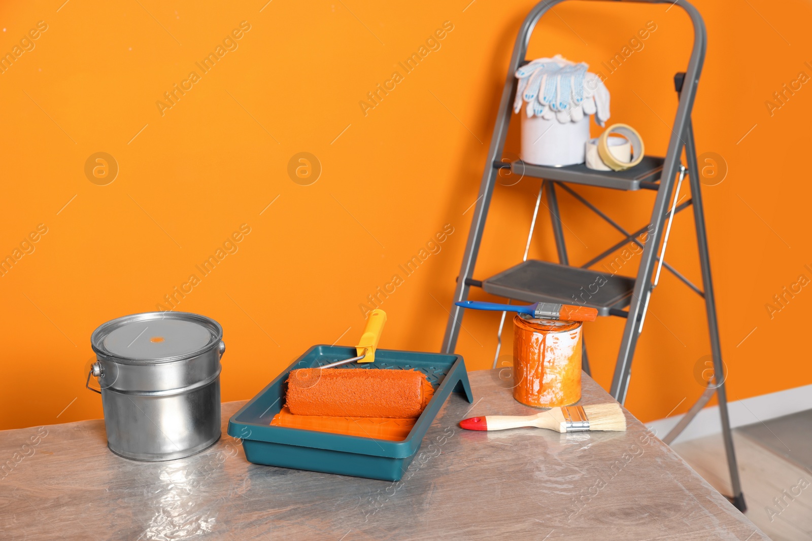 Photo of Tray with orange paint and roller on table