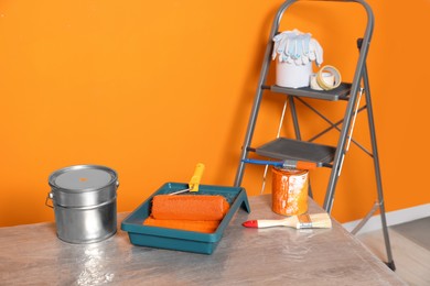 Tray with orange paint and roller on table