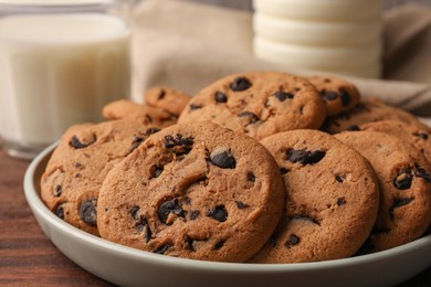 Photo of Delicious chocolate chip cookies and milk on wooden table, closeup