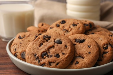 Delicious chocolate chip cookies and milk on wooden table, closeup