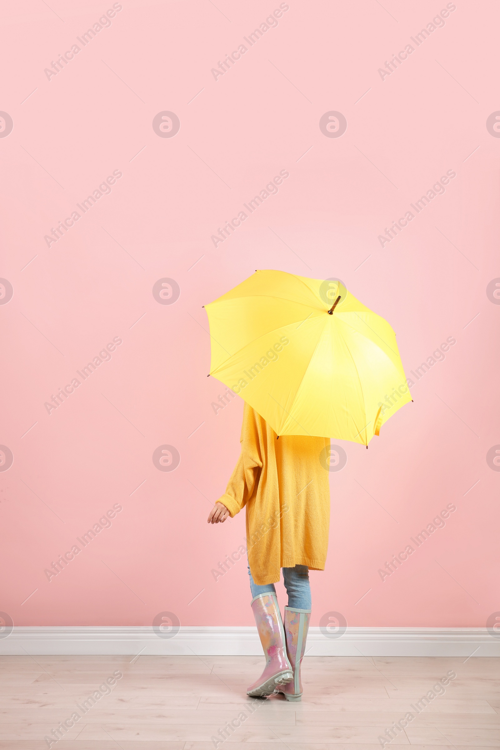 Photo of Woman with yellow umbrella near color wall