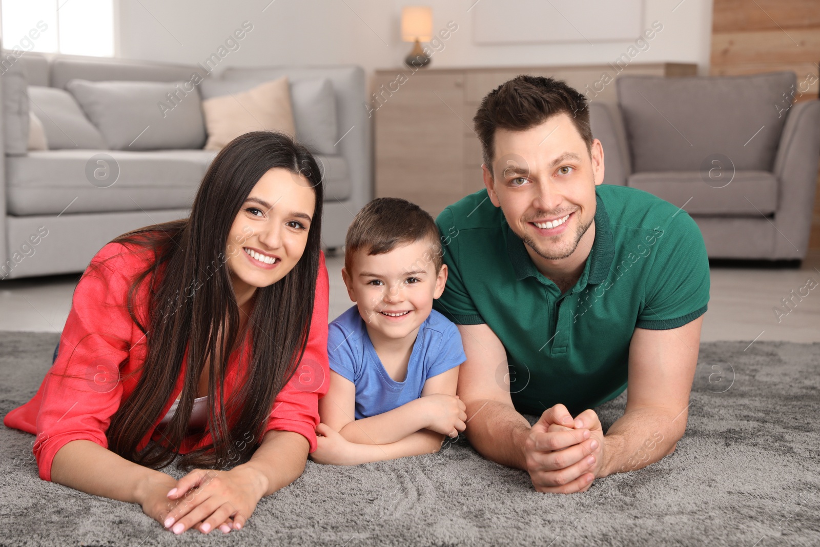 Photo of Happy parents and their son lying together on floor at home. Family weekend