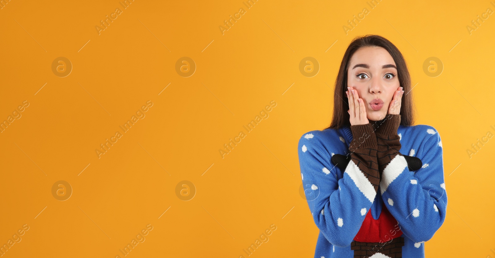 Photo of Surprised young woman in Christmas sweater on yellow background, space for text