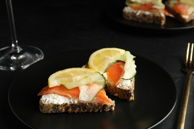Photo of Delicious bruschettas with salmon served on black table