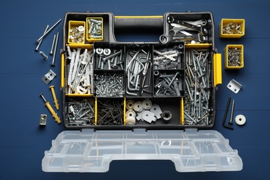 Organizer with many different fasteners and wrenches on blue wooden table, flat lay