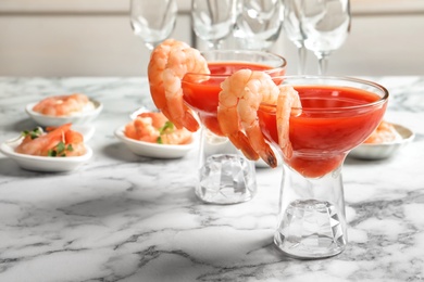 Photo of Glasses with boiled shrimps and tomato sauce on table