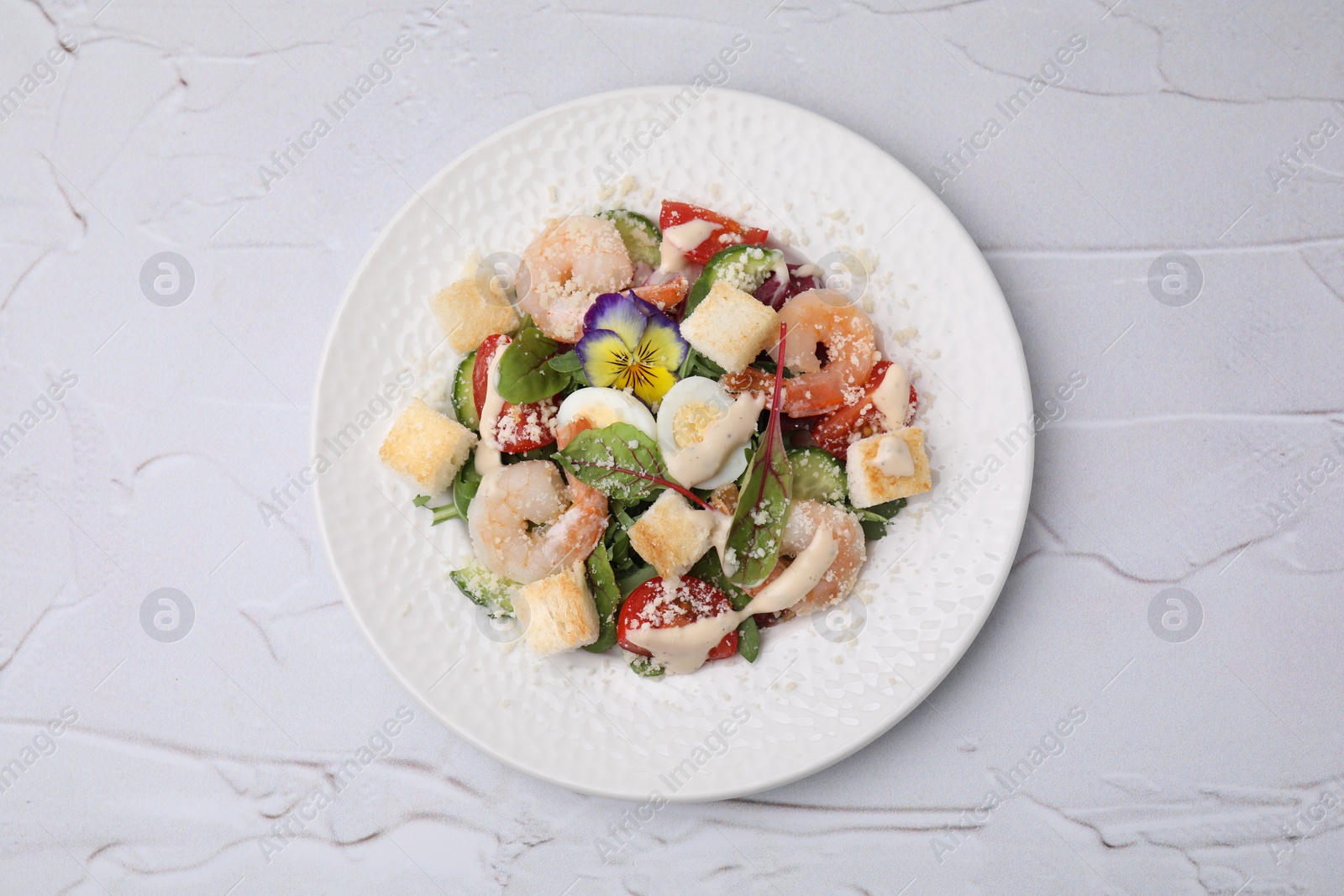 Photo of Delicious Caesar salad with shrimps on white textured table, top view