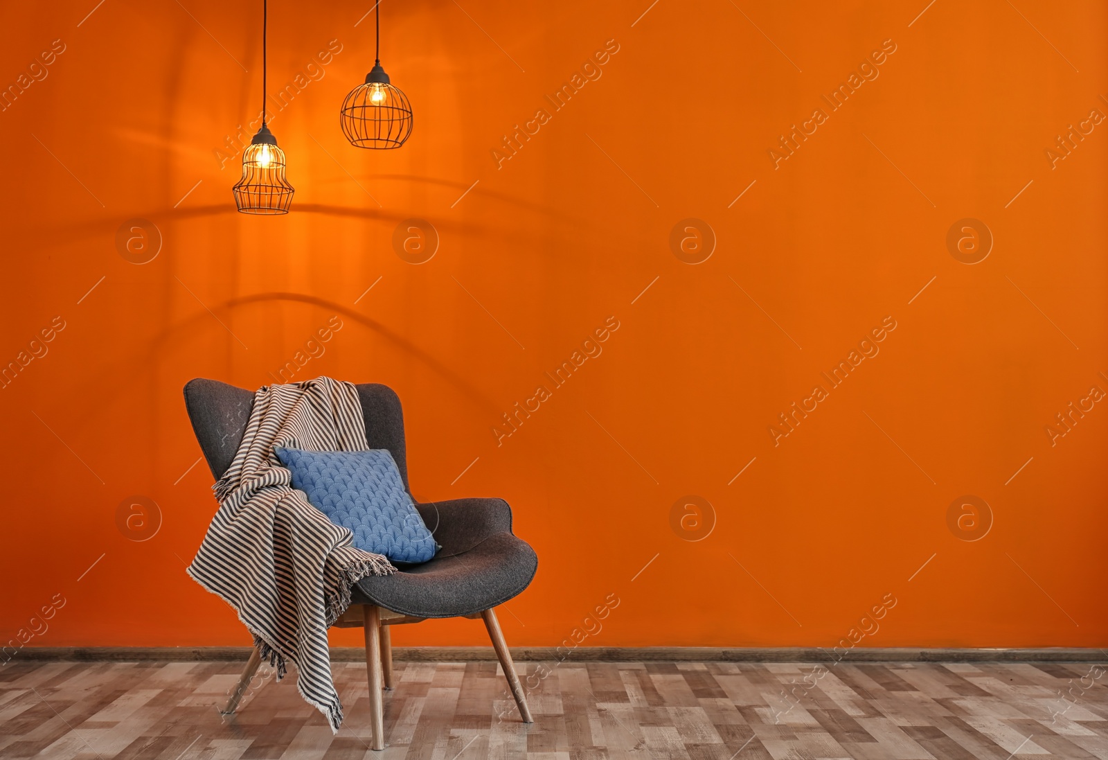 Photo of Armchair with pillow and plaid near color wall in room