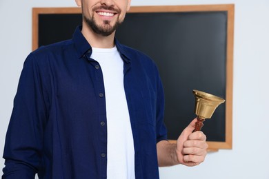 Photo of Teacher with school bell near black chalkboard, closeup