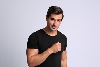 Photo of Portrait of handsome young man in black t-shirt on grey background