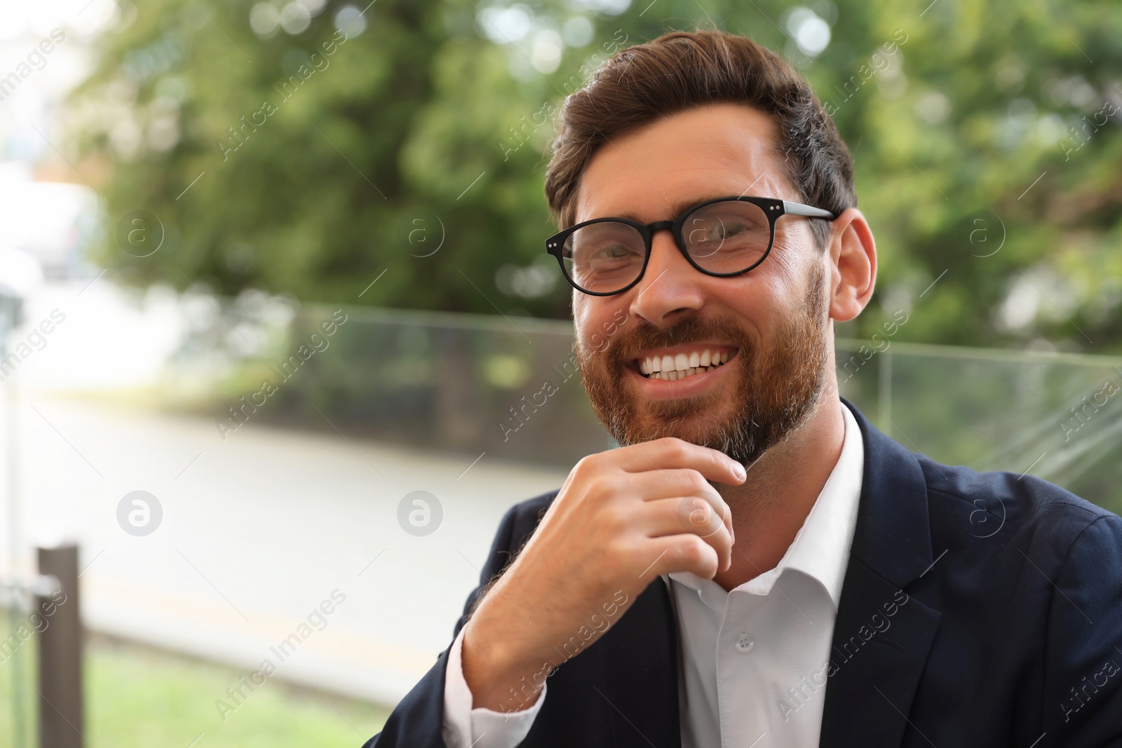 Photo of Smiling handsome bearded man with glasses outdoors. Space for text