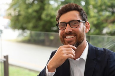 Photo of Smiling handsome bearded man with glasses outdoors. Space for text