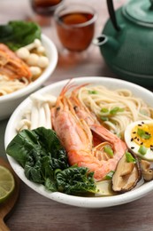 Photo of Delicious ramen with shrimps and egg in bowl on wooden table, closeup. Noodle soup