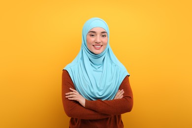 Portrait of Muslim woman in hijab on orange background