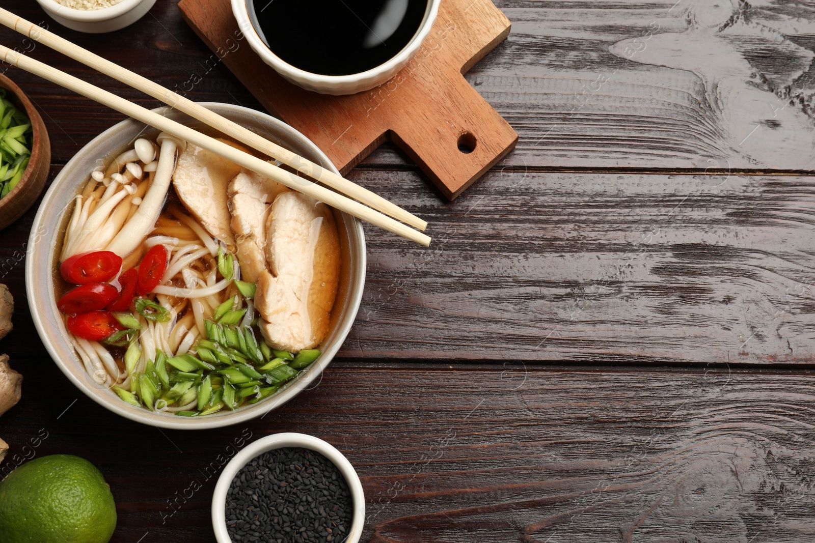 Photo of Delicious ramen with meat and ingredients on wooden table, flat lay. Space for text