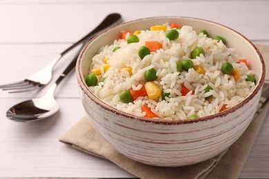 Photo of Bowl of delicious rice with vegetables served on white wooden table, closeup