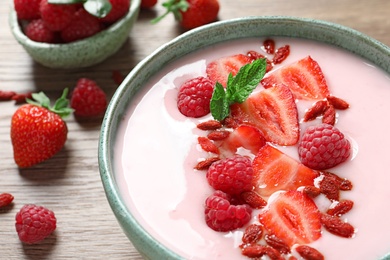 Photo of Smoothie bowl with goji berries on wooden table, closeup