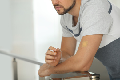 Photo of Man with nicotine patch and cigarette indoors, closeup