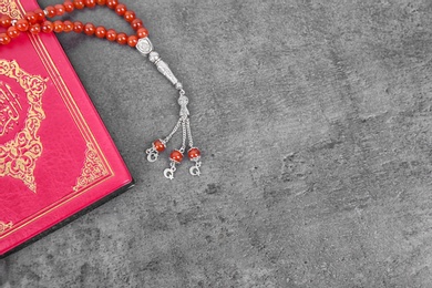 Muslim prayer beads, Quran and space for text on grey background, top view