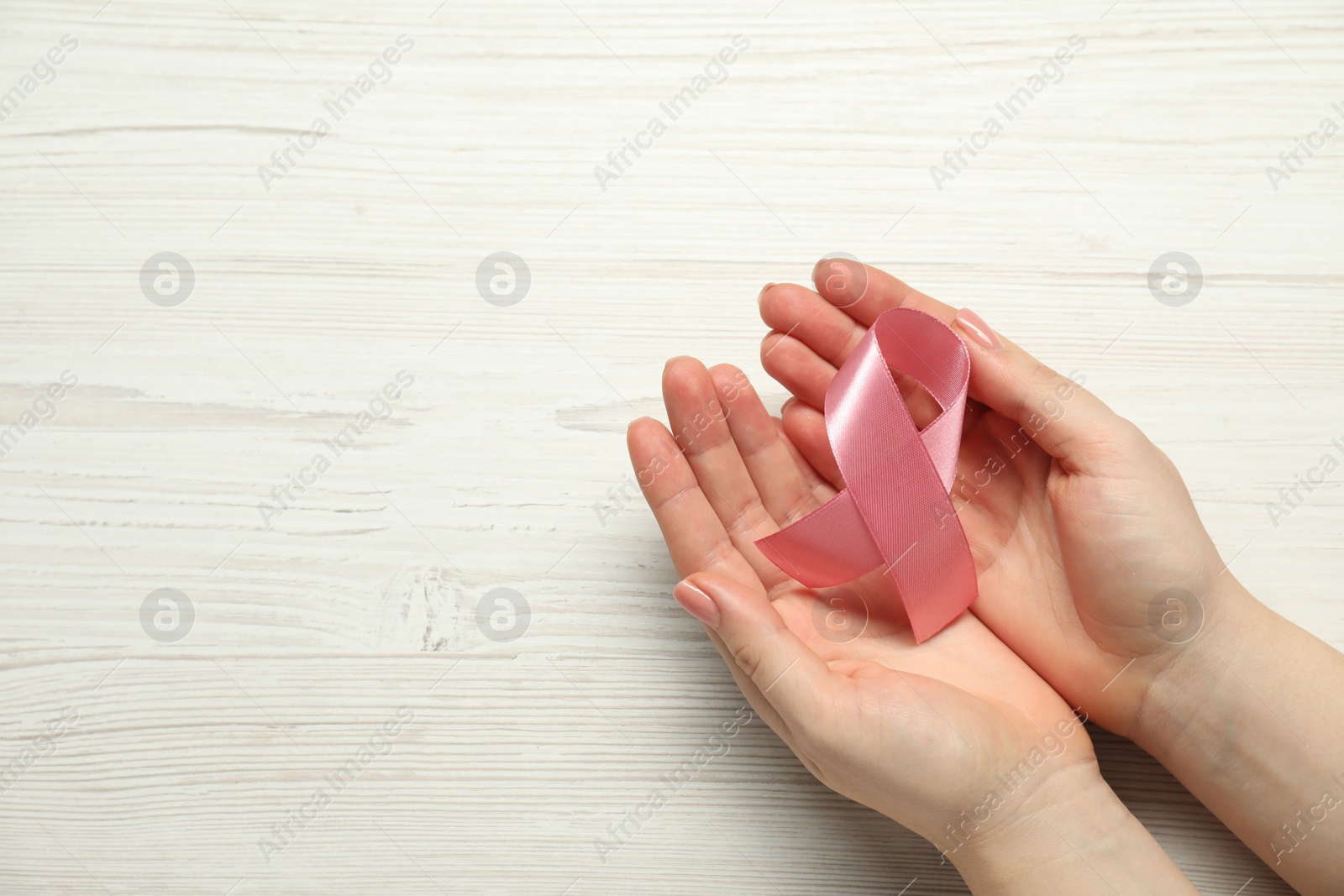 Photo of Breast cancer awareness. Woman with pink ribbon at white wooden table, top view. Space for text