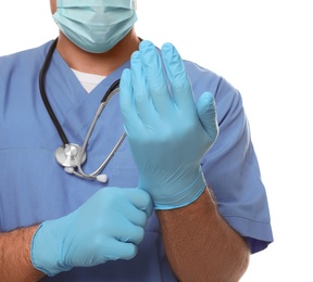 Doctor in protective mask putting on medical gloves against white background, closeup