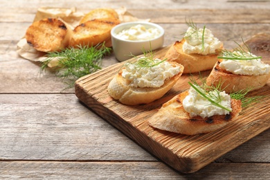 Photo of Toasted bread with tasty cream cheese on wooden table