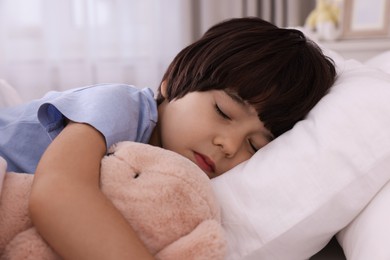Photo of Cute little boy with toy bear sleeping in bed at home