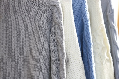 Photo of Collection of warm sweaters as background, closeup