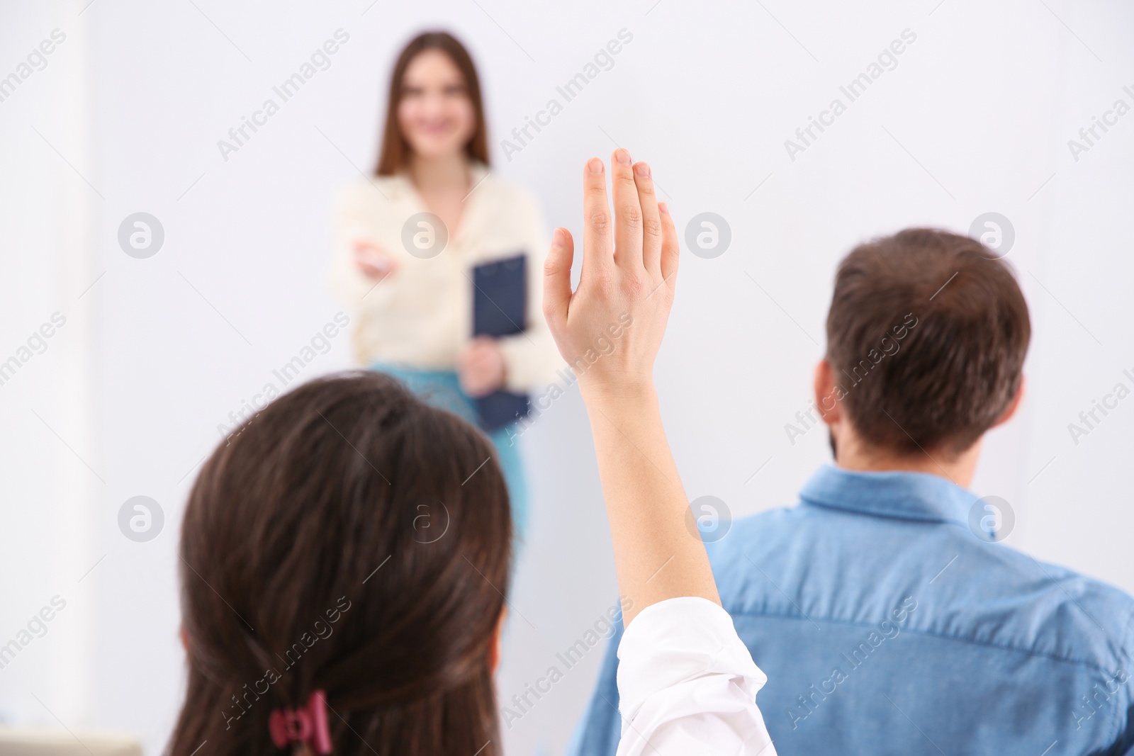 Photo of Young woman raising hand to ask question at business training indoors, closeup