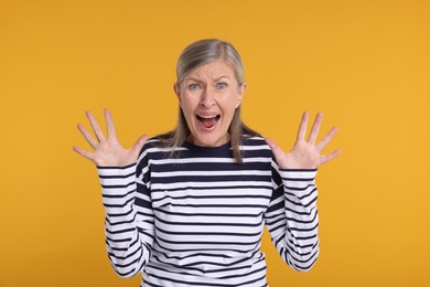 Portrait of surprised senior woman on yellow background