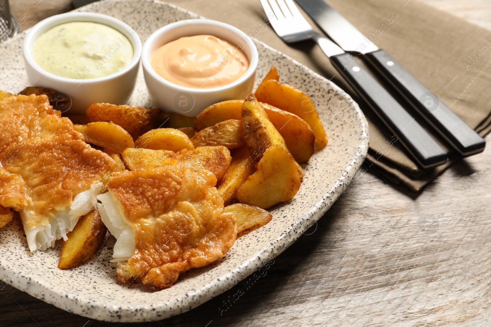 Photo of Plate with British traditional fish and potato chips on wooden table, closeup