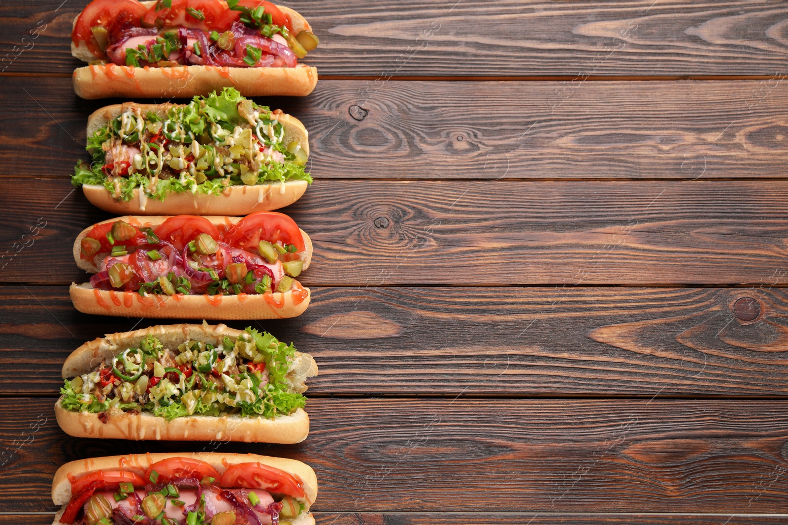 Photo of Different tasty hot dogs on wooden table, flat lay. Space for text