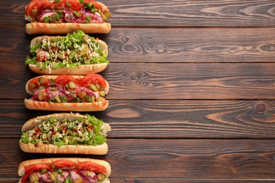Different tasty hot dogs on wooden table, flat lay. Space for text
