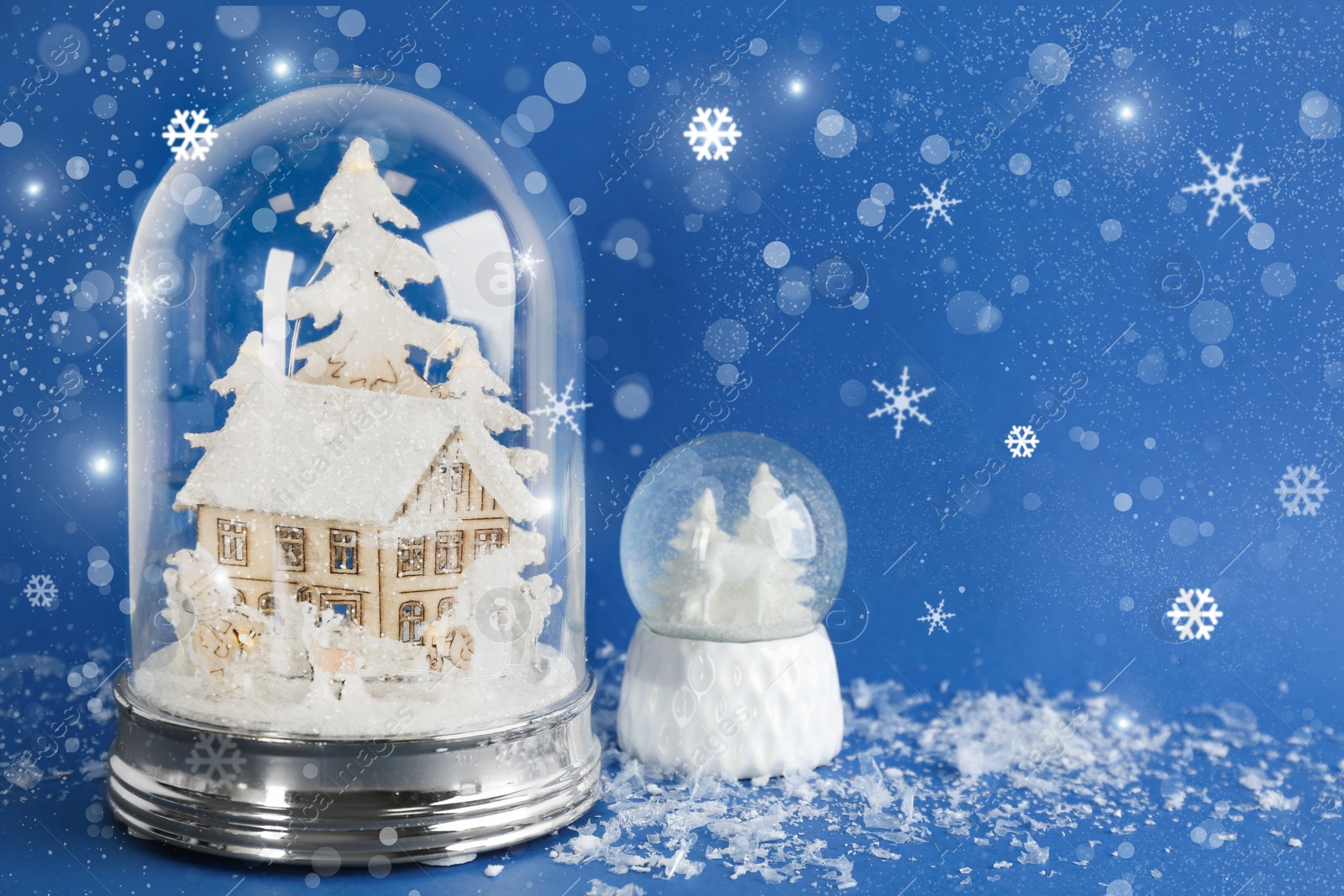 Image of Beautiful Christmas snow globes on blue background, bokeh effect. Space for text