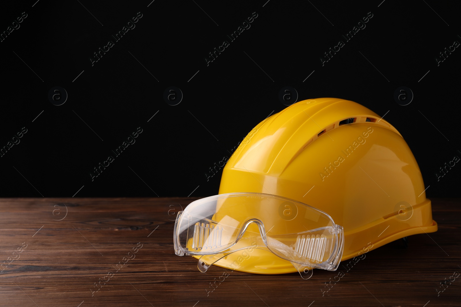 Photo of Safety equipment. Hard hat and goggles on wooden table, space for text
