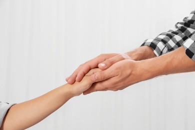 Man holding woman's hand on light background. Concept of support and help