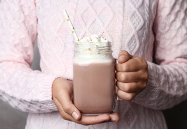 Woman holding mason jar of delicious cocoa drink with marshmallows, closeup