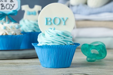Photo of Beautifully decorated baby shower cupcake for boy with cream on white wooden table