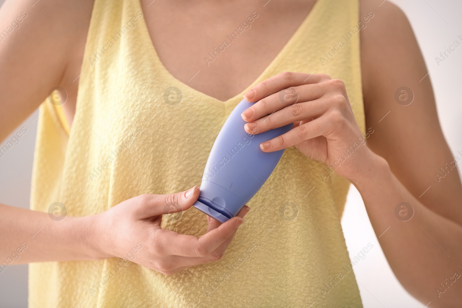 Photo of Young woman holding bottle with hand cream, closeup