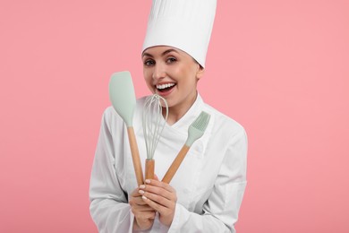 Photo of Happy confectioner in uniform holding professional tools on pink background