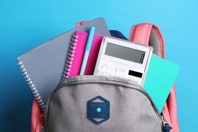 Photo of Backpack with different school stationery on light blue background